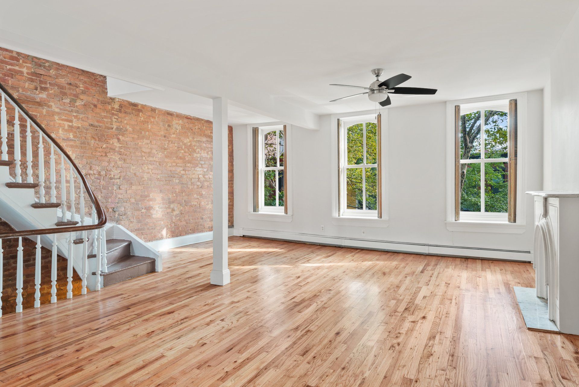 An empty living room with hardwood floors and a ceiling fan.