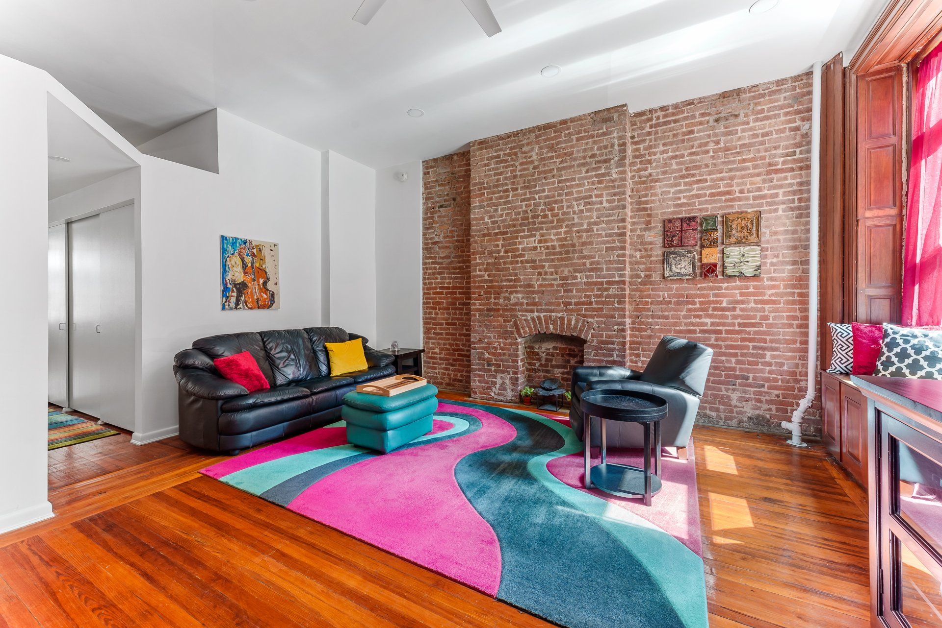 A living room with a couch , chair , rug and fireplace.