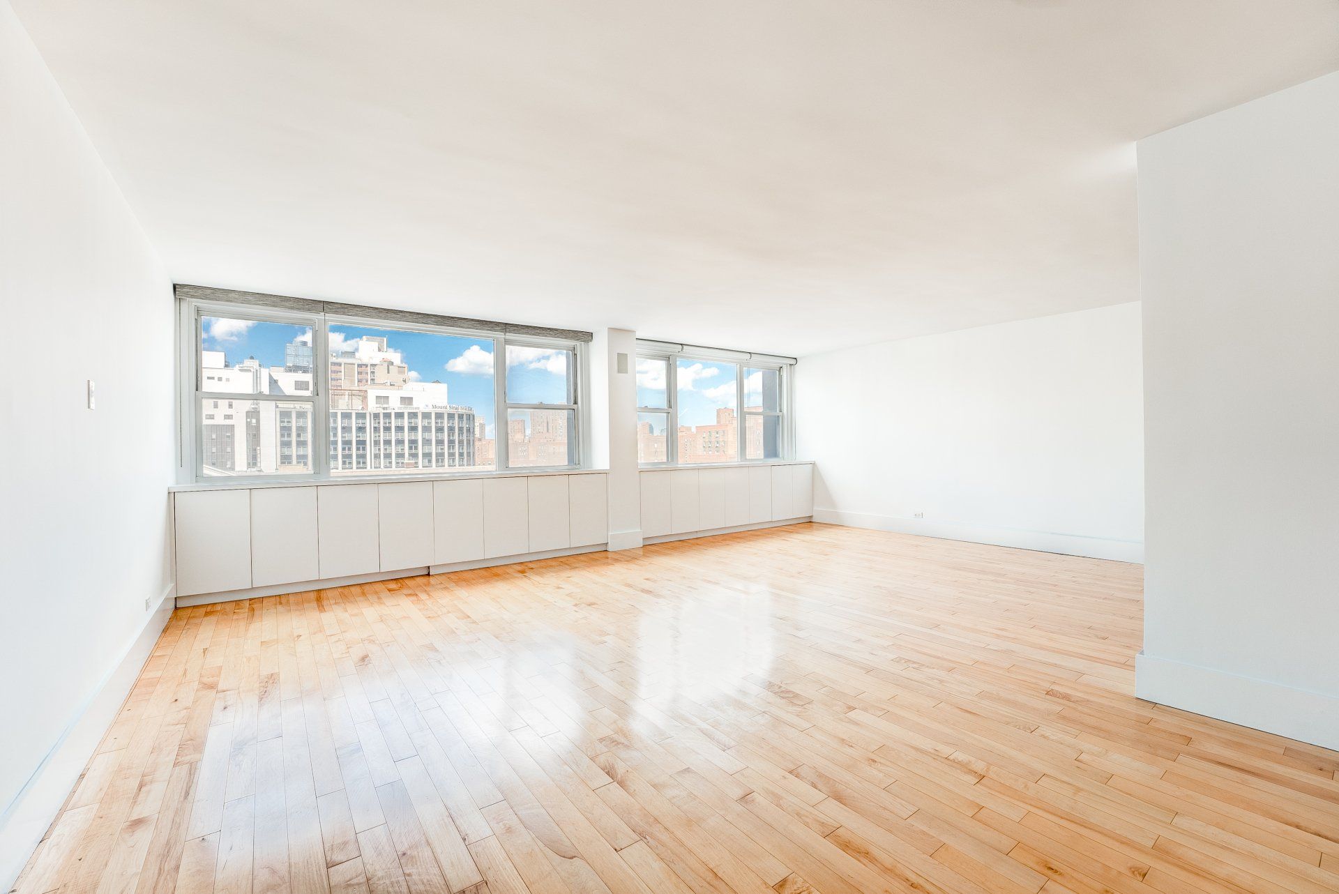 A large empty room with hardwood floors and lots of windows