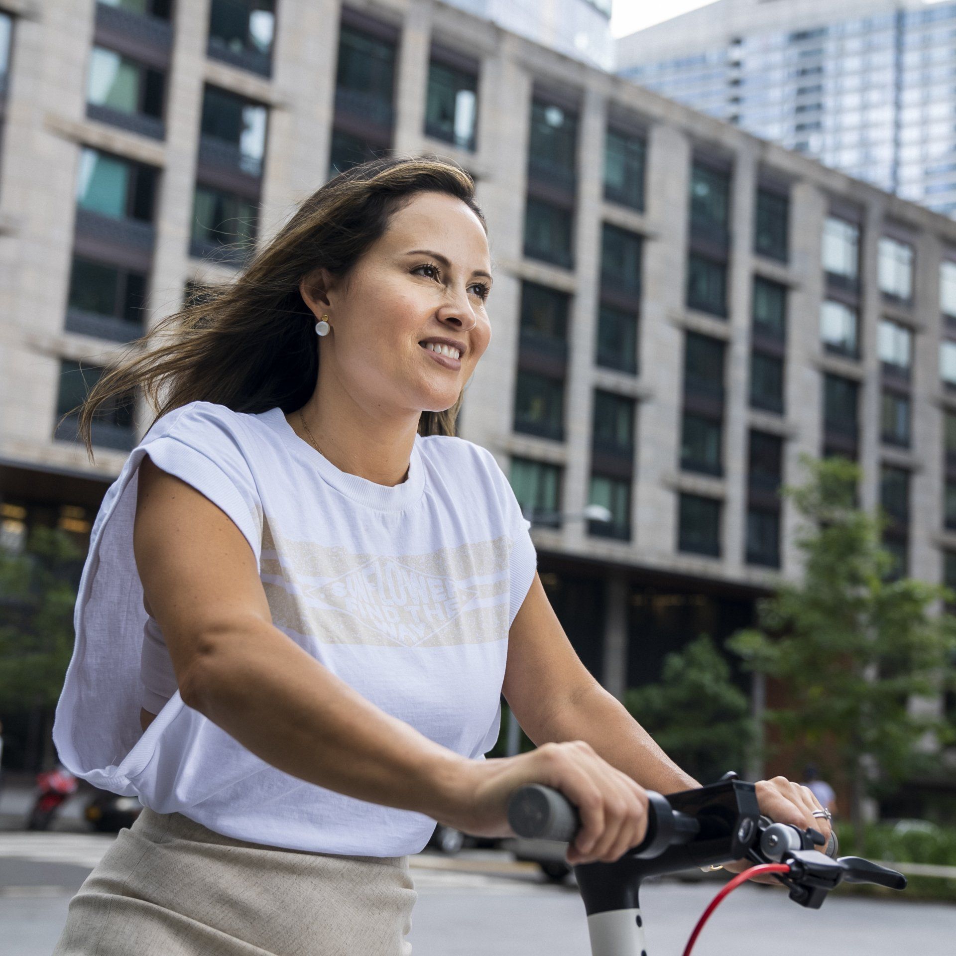 A woman is riding a scooter down a city street.