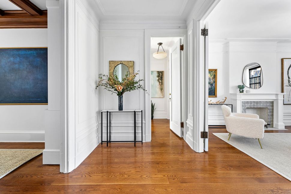 A living room with hardwood floors , white walls and a fireplace.