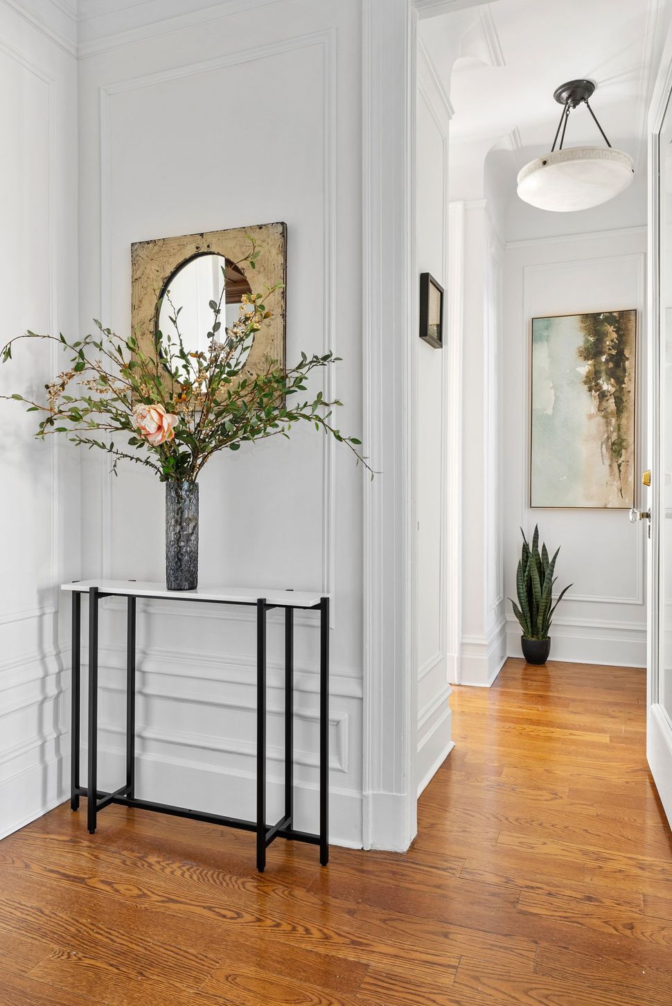 There is a vase of flowers on the table in the hallway.