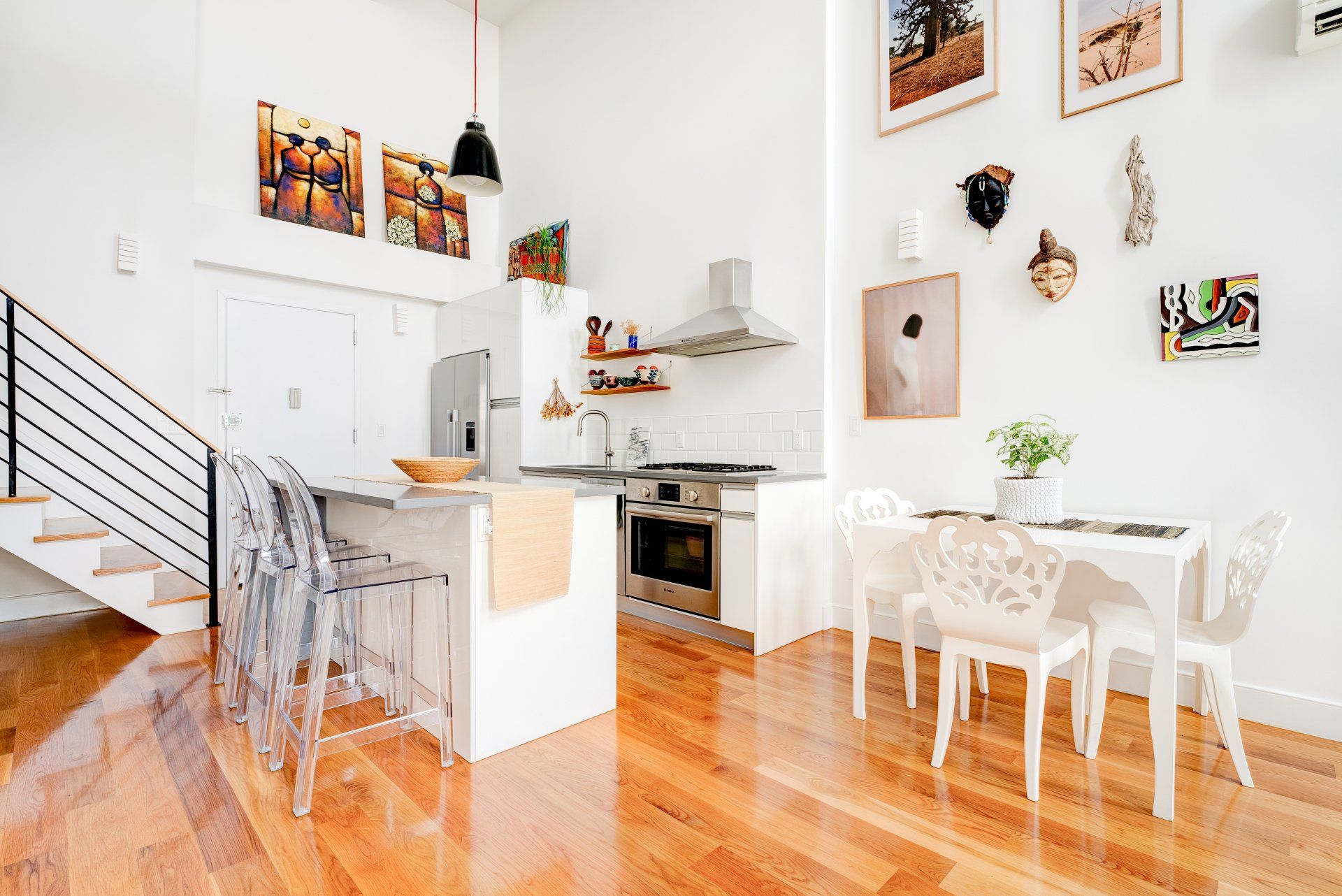 A kitchen with a table and chairs and a staircase leading to the second floor.