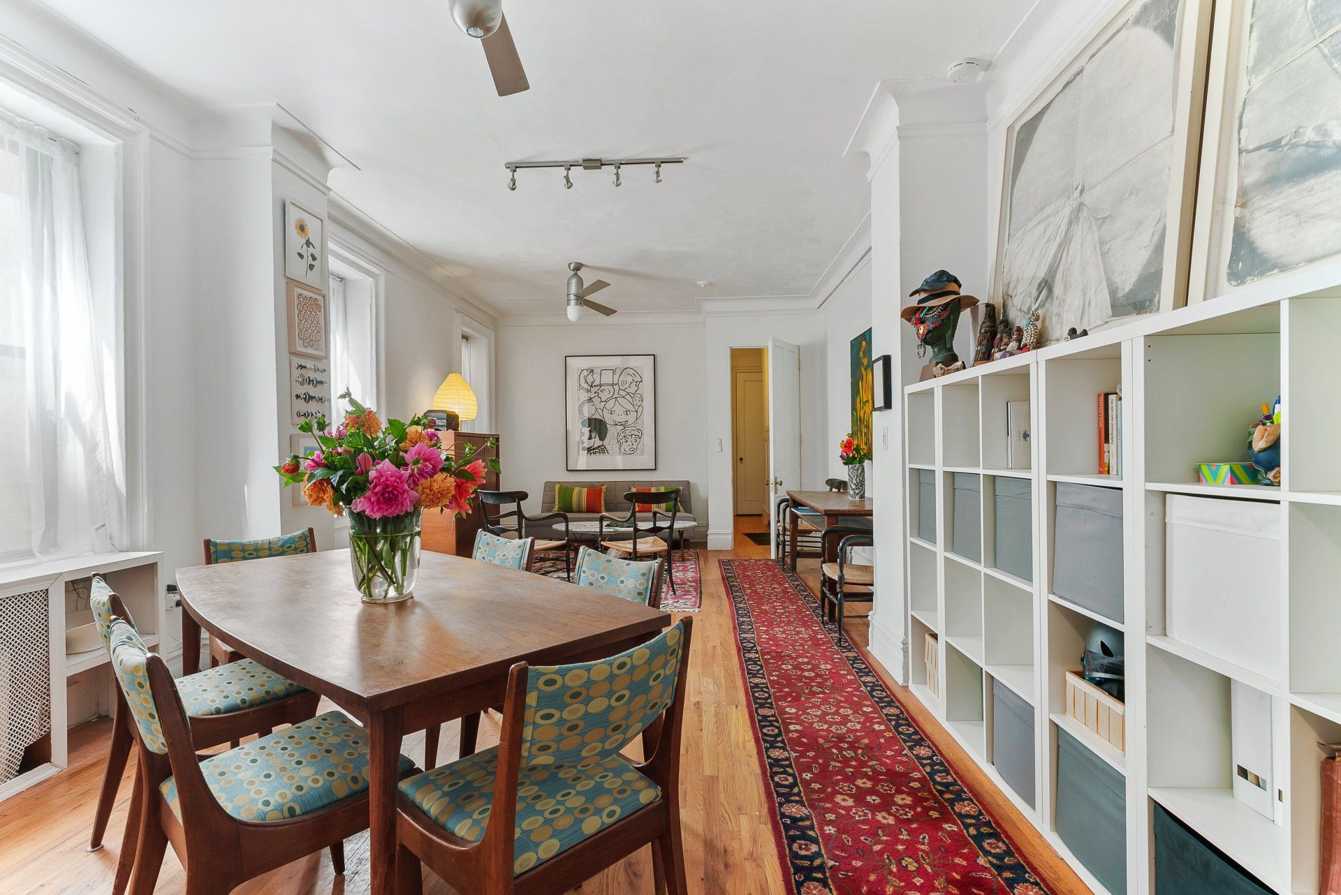 A living room with a table and chairs and a vase of flowers on the table.