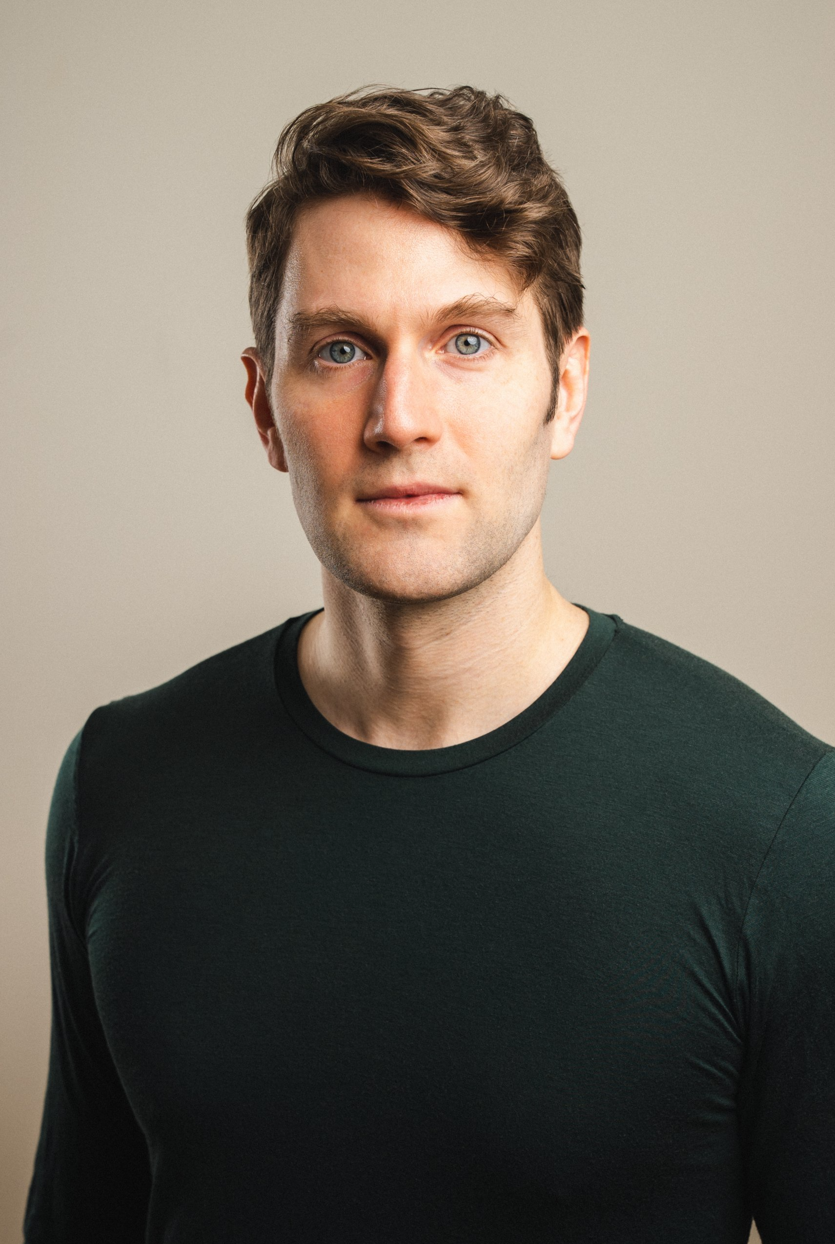A man in a green sweater is looking at the camera.