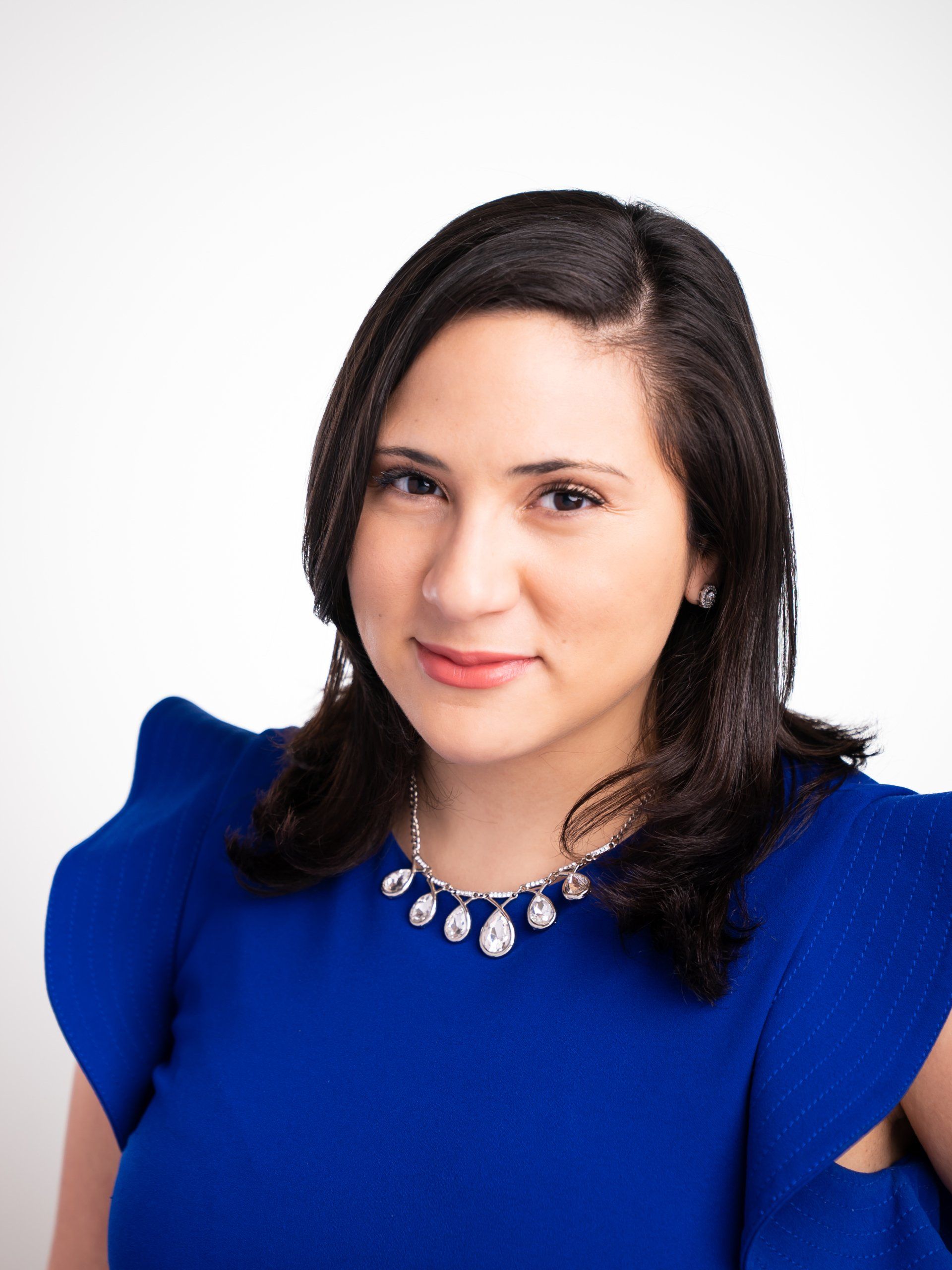A woman is wearing a blue top and a necklace
