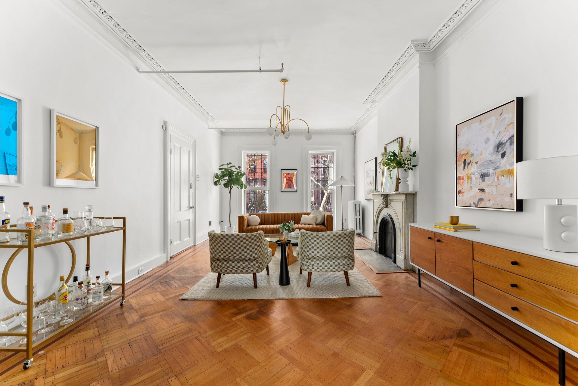 A living room with a couch , chairs , a fireplace and a bar cart.