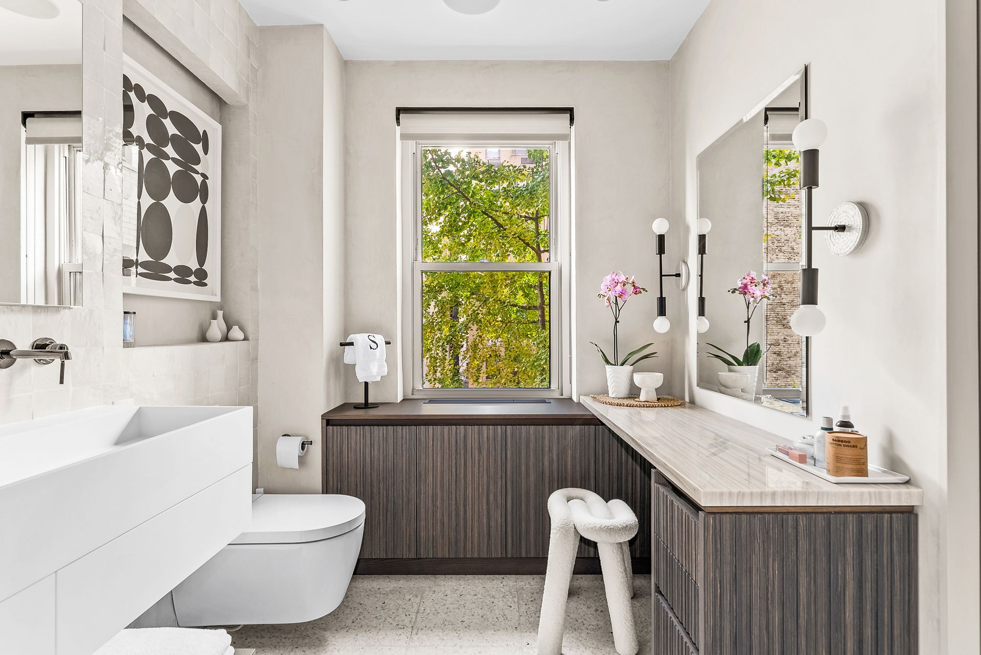 A bathroom with a toilet , sink , mirror and window.