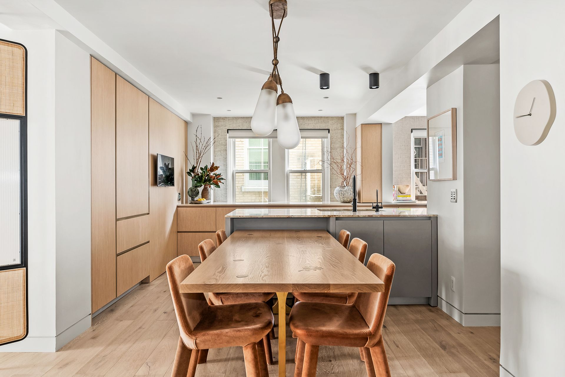 A kitchen with a wooden table and chairs and a clock on the wall.
