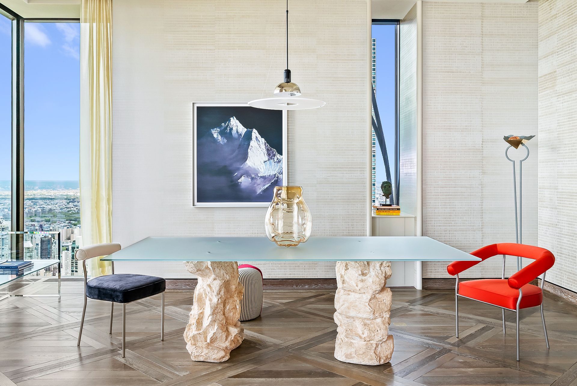 A dining room with a table and chairs and a painting on the wall.