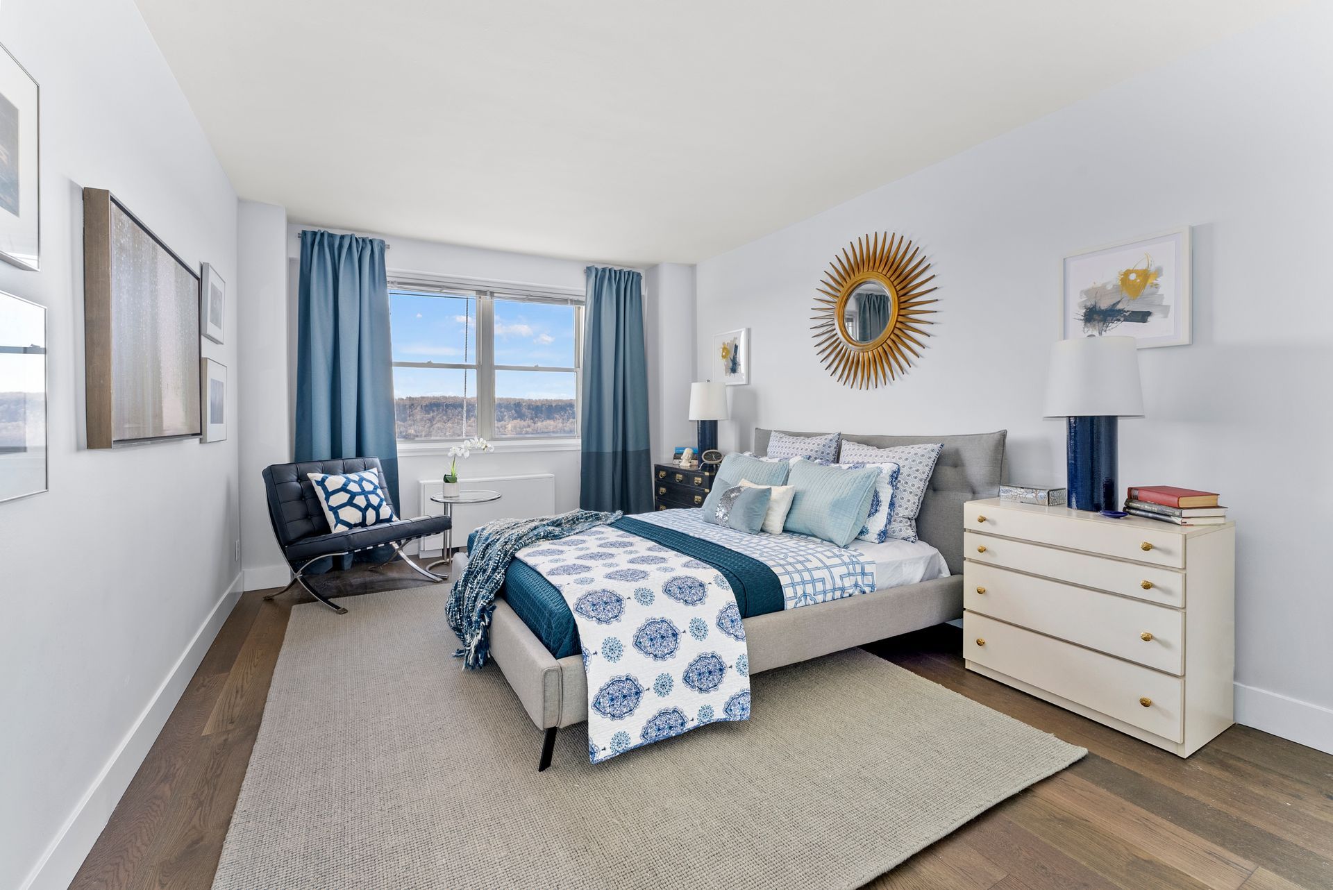A bedroom with a bed , dresser , chair and window.
