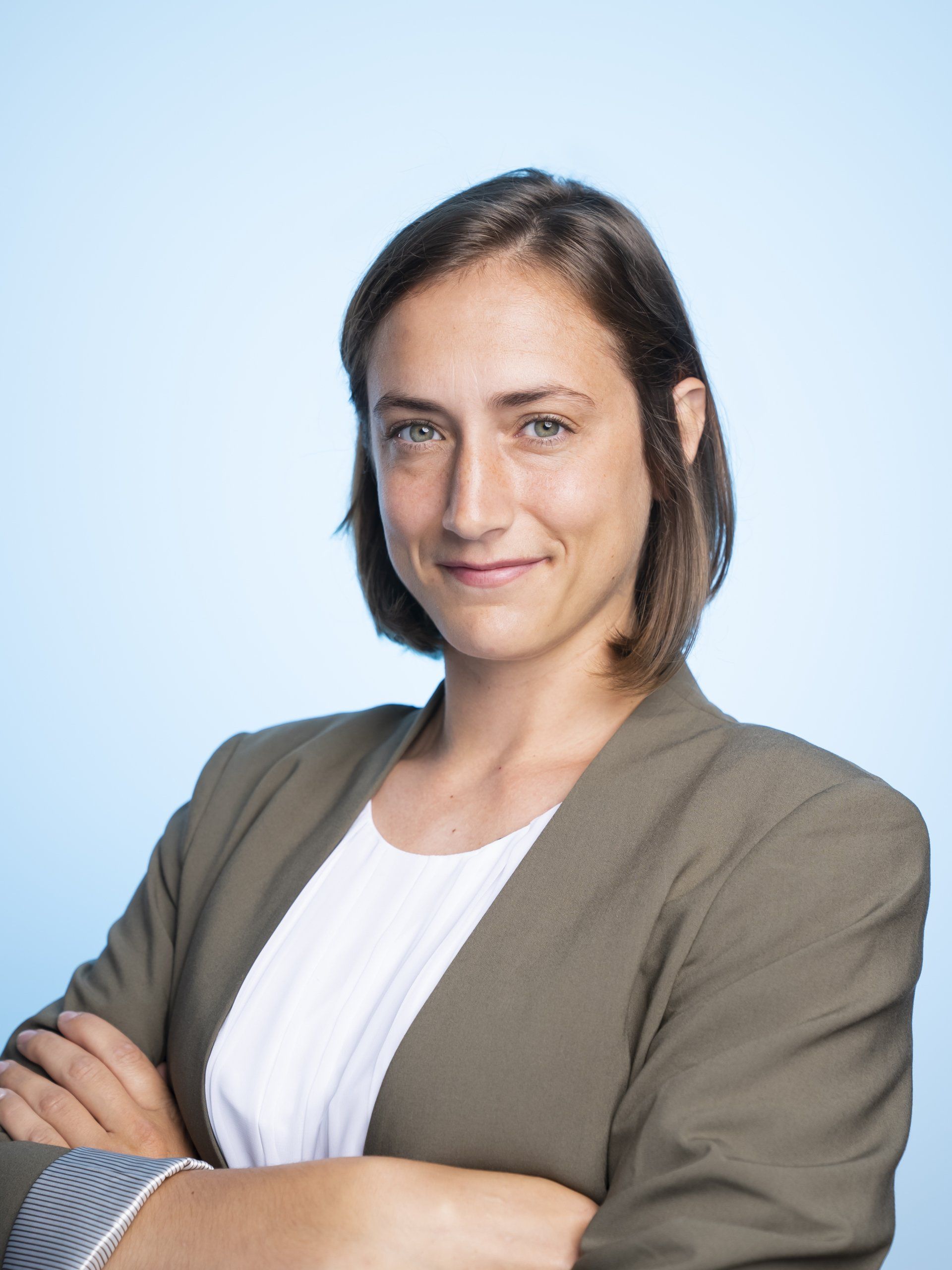 A woman with her arms crossed is smiling for the camera.