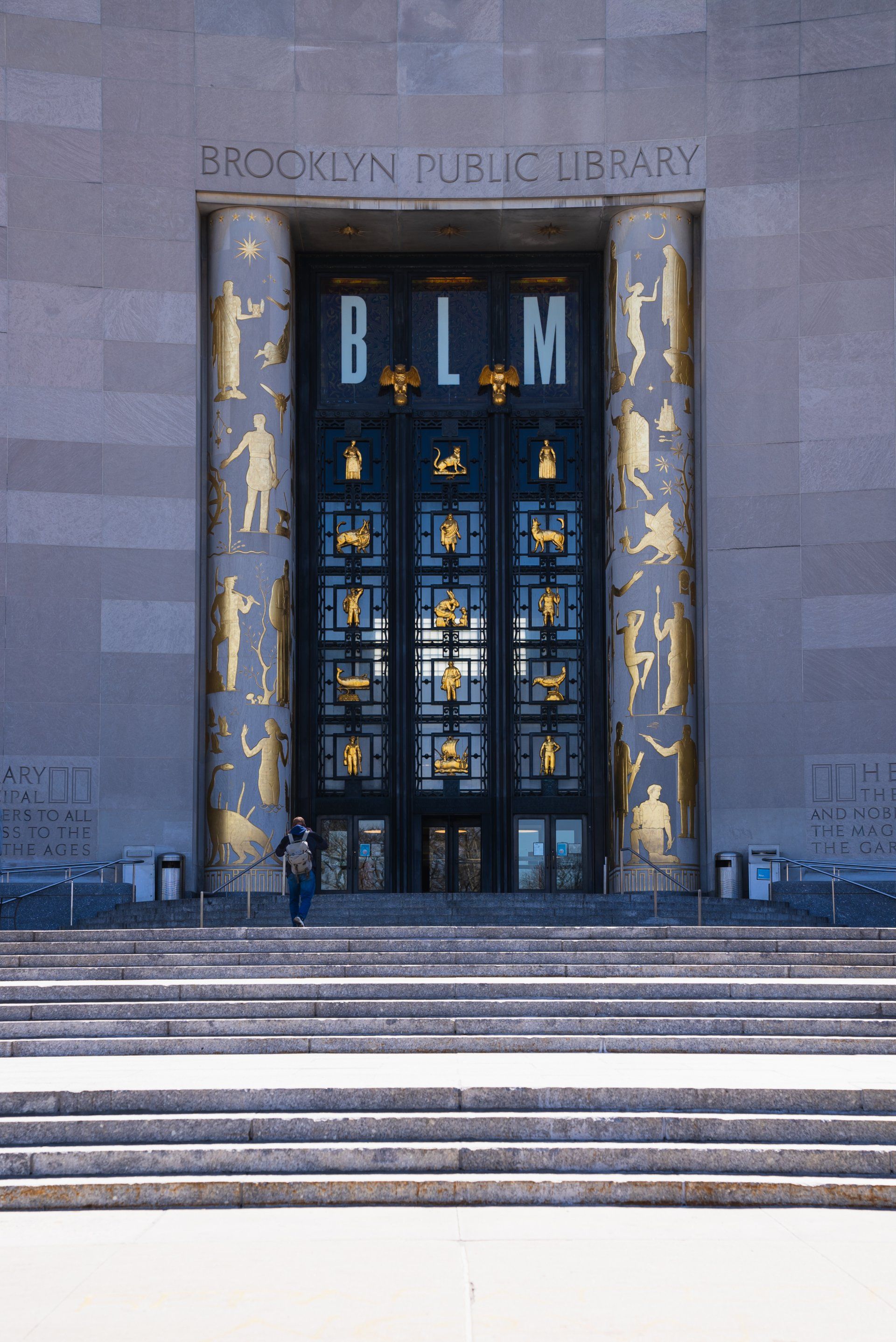 A person is standing in front of the entrance to the brooklyn public library