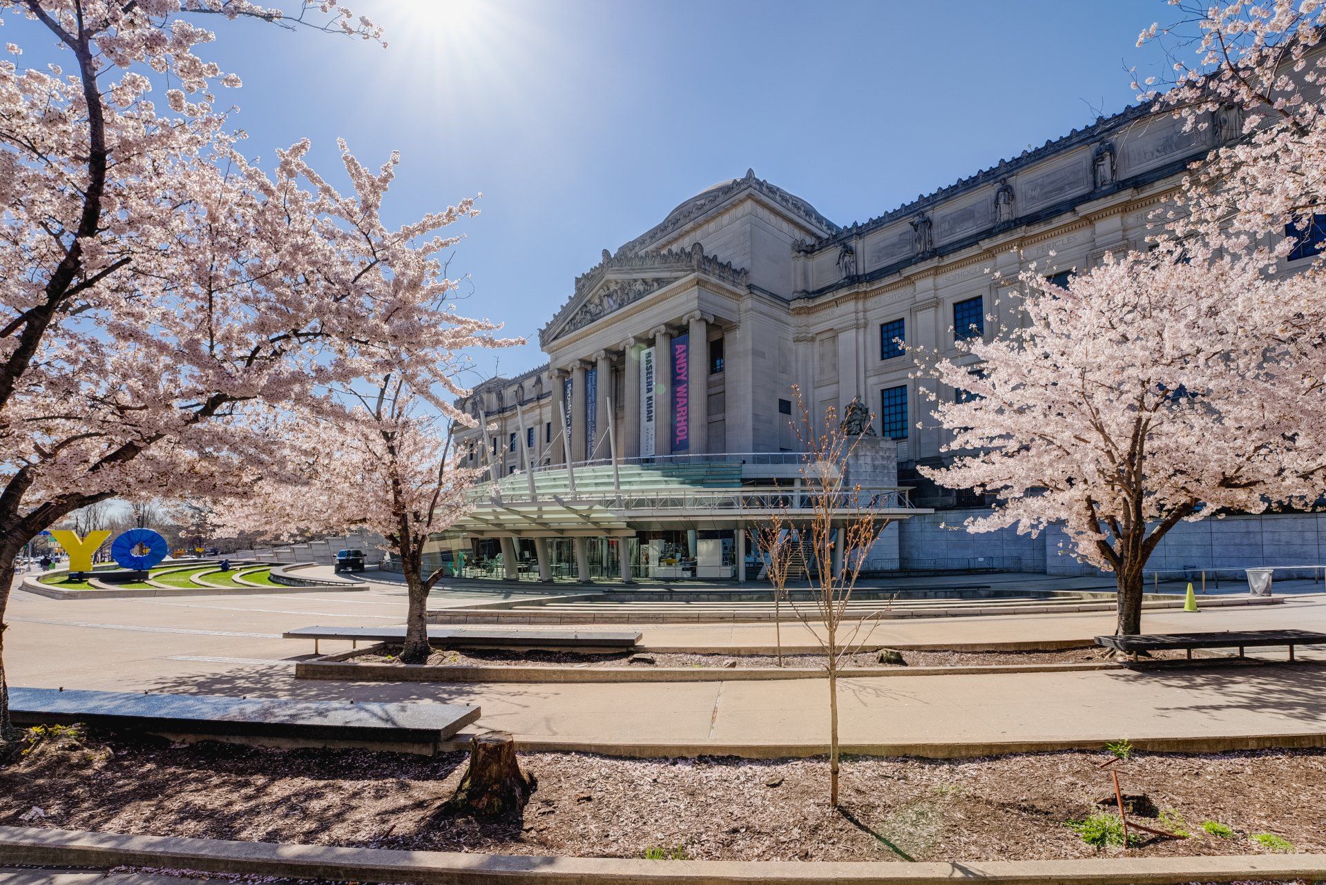 A large building with cherry blossom trees in front of it.