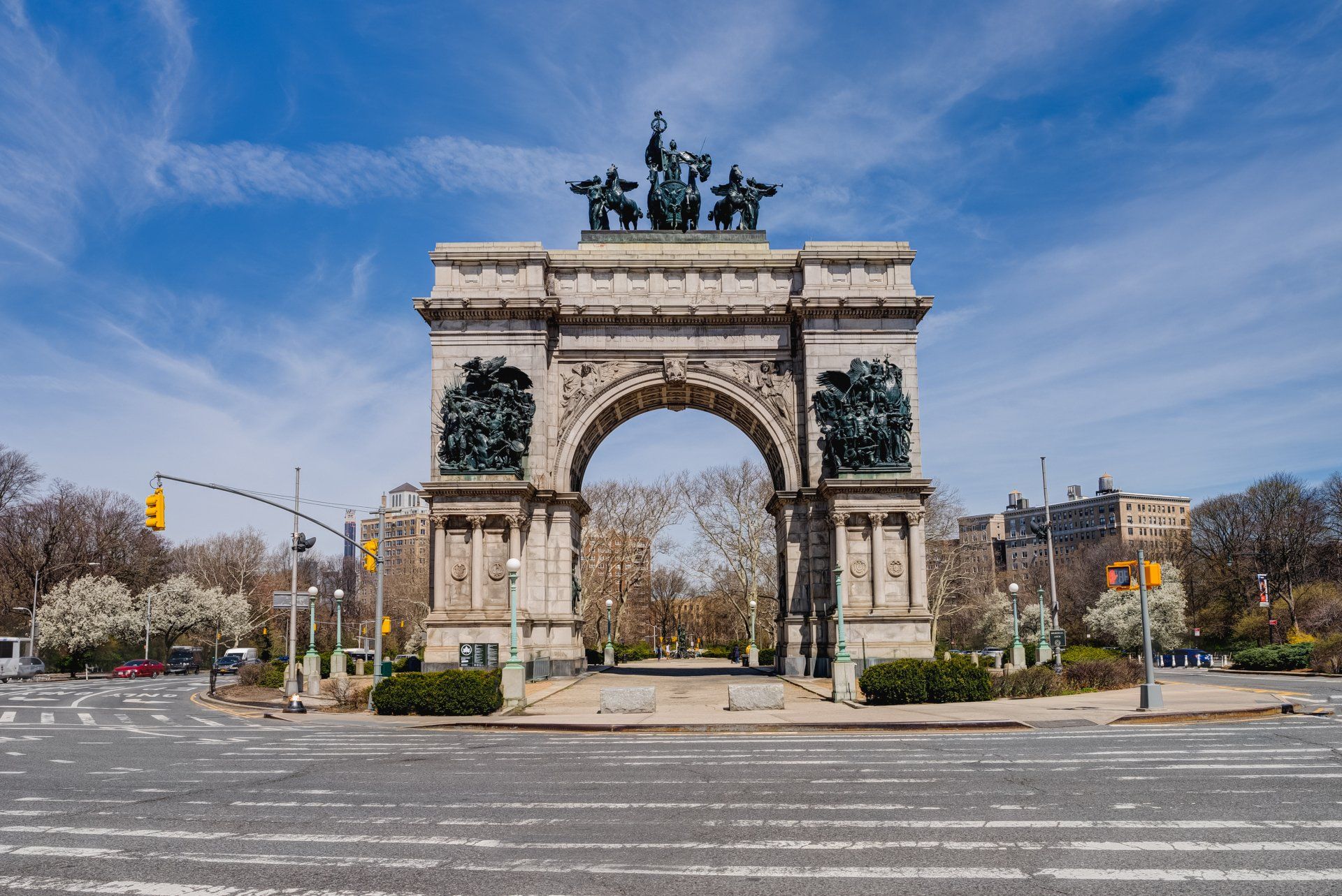 A large archway with a statue on top of it is in the middle of a city street.