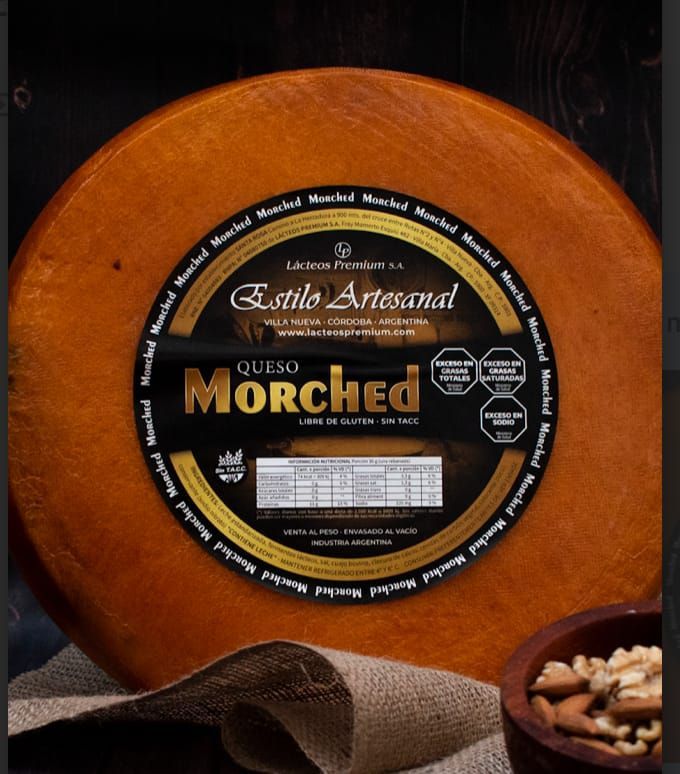 Rueda redonda de queso artesano “Morched” con etiqueta negra y dorada, sobre superficie de arpillera.