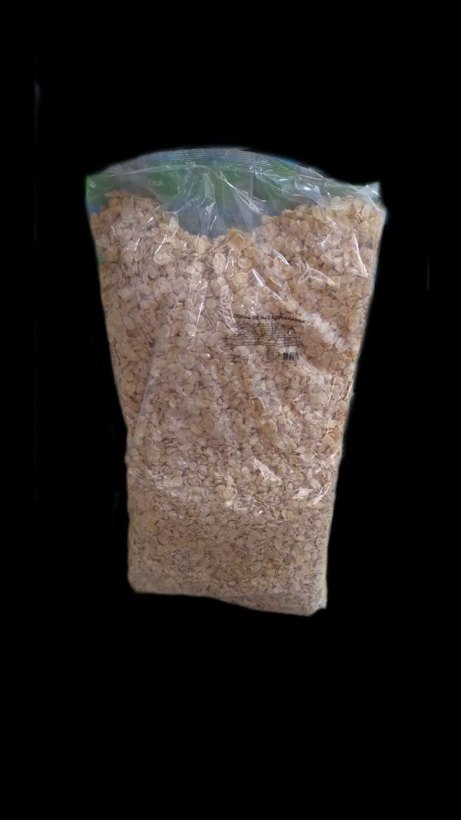 Una bolsa de plástico transparente llena de material beige sobre un fondo negro.