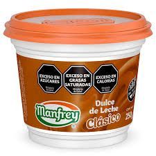 Un envase de Dulce de Leche Clásico Manfrey, con etiquetas de advertencia sobre azúcar, grasas saturadas y calorías.