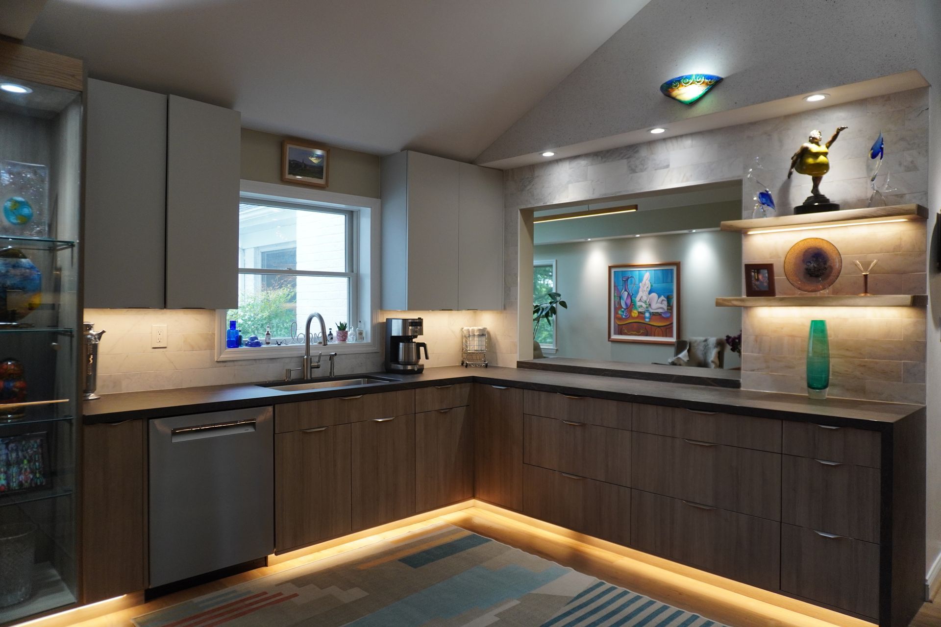 Modern kitchen with dark wood cabinets, black countertops, and warm under-cabinet lighting.