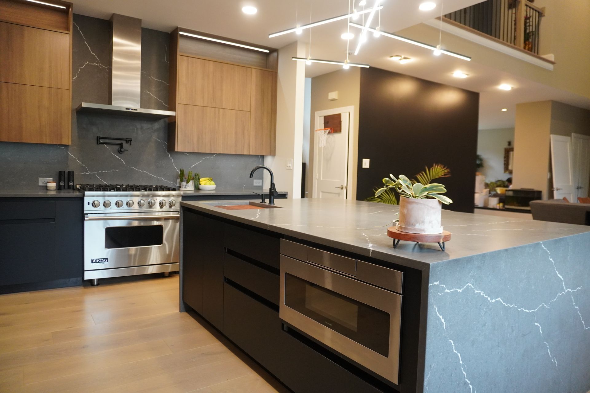 Modern kitchen with dark cabinets, stainless steel stove, and large island with blue marble sides.