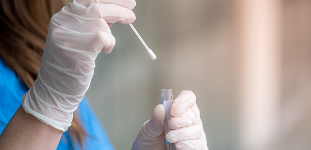 Gloved hands holding a swab and test tube during a lab or medical sample collection