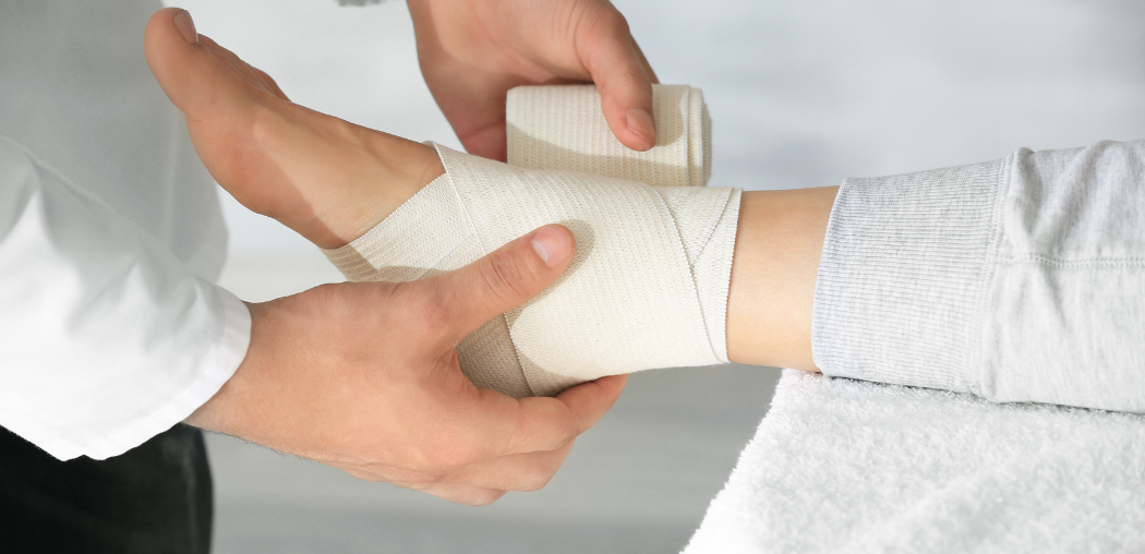 Hands wrapping a white bandage around a person’s wrist and forearm
