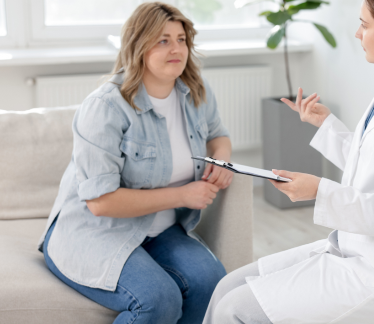 Woman consulting with a doctor on a couch in a bright clinic office, clipboard in hand.