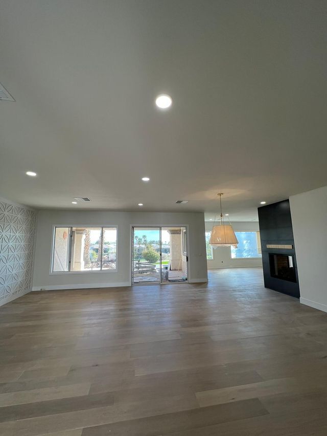 Open-concept living space with light wood floors, a fireplace, and a sliding glass door to a patio.