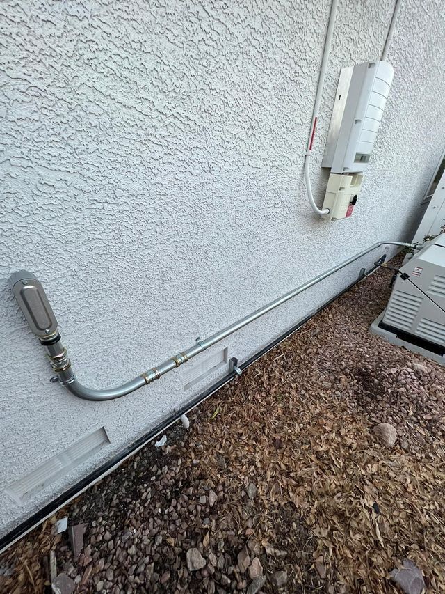 Electrical conduit and junction box along a stucco wall.