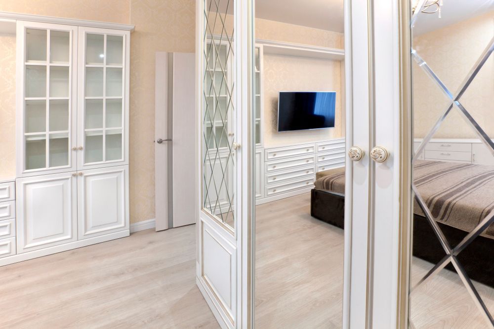 A Bedroom With a Bed, Television and Mirrored Doors — Whitsunday Architectural Windows & Doors in Airlie Beach, QLD