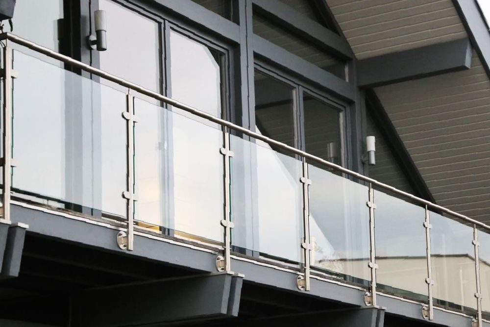 A Little Girl is Standing on a Balcony Looking Out Over a City — Whitsunday Architectural Windows & Doors in Cannonvale, QLD