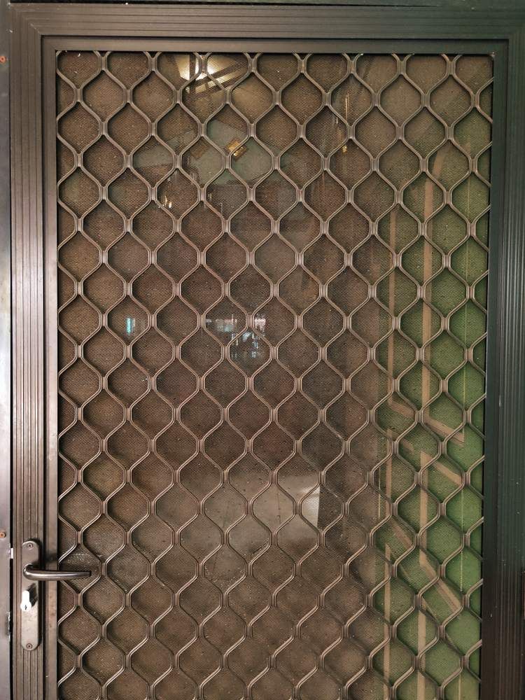 A Close Up of a Metal Gate With a Grid Pattern on It — Whitsunday Architectural Windows & Doors in Cannonvale, QLD