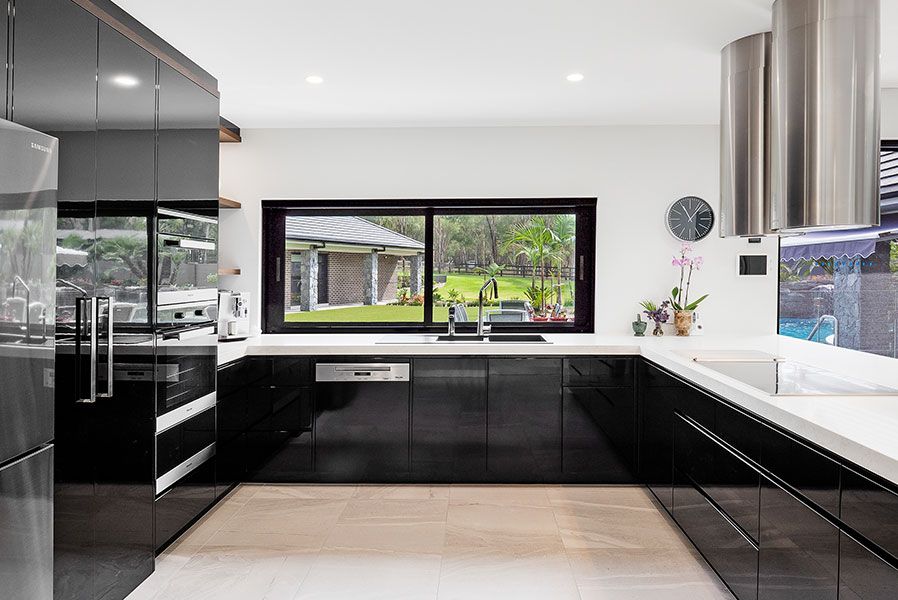 A Modern House With a Black Roof is Sitting on Top of a Lush Green Field — Whitsunday Architectural Windows & Doors in Proserpine, QLD