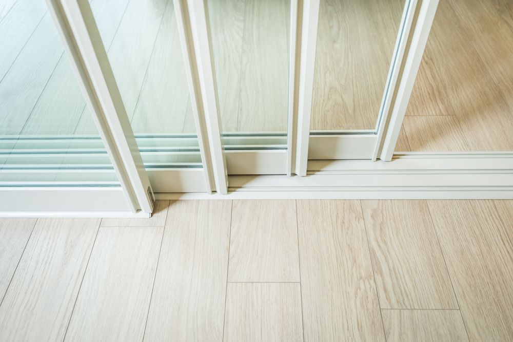 A Close Up of a Sliding Glass Door in a Room With a Wooden Floor — Whitsunday Architectural Windows & Doors in Proserpine, QLD