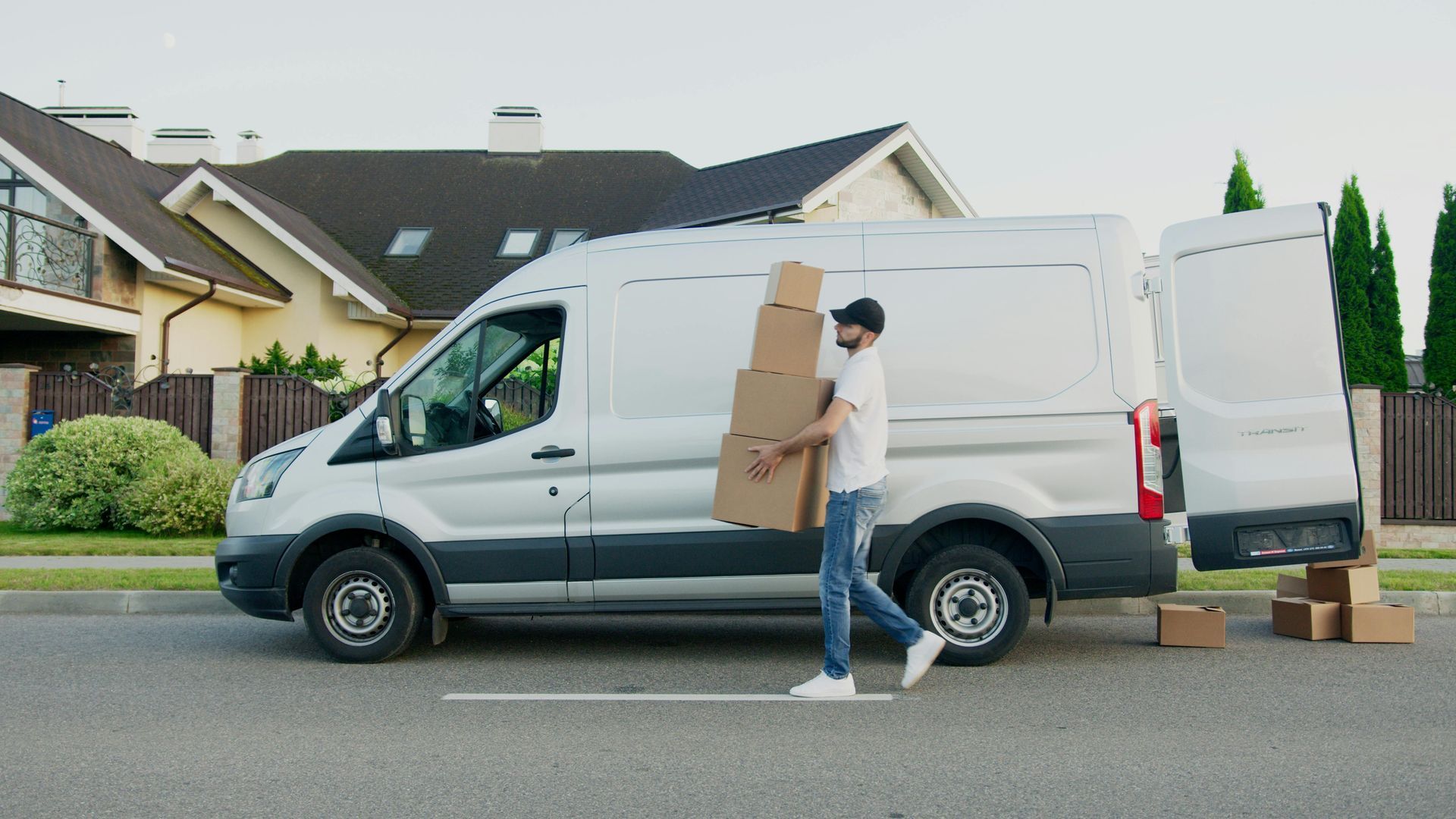 A delivery man is carrying boxes out of a white van.
