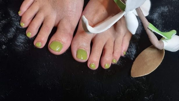 Een close-up van de voeten van een vrouw met groene nagellak.