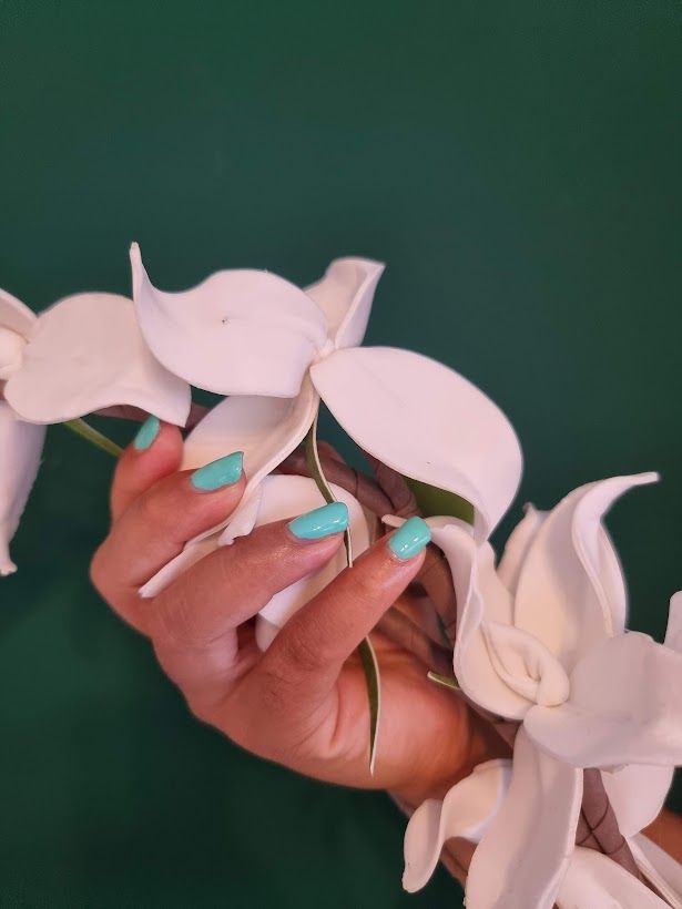 Een vrouw met blauwe nagels houdt een bos witte bloemen vast