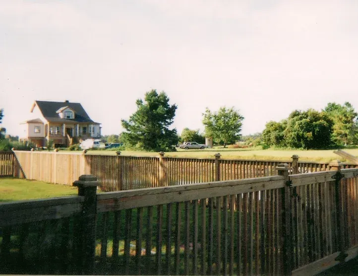 A wooden fence with a house in the background