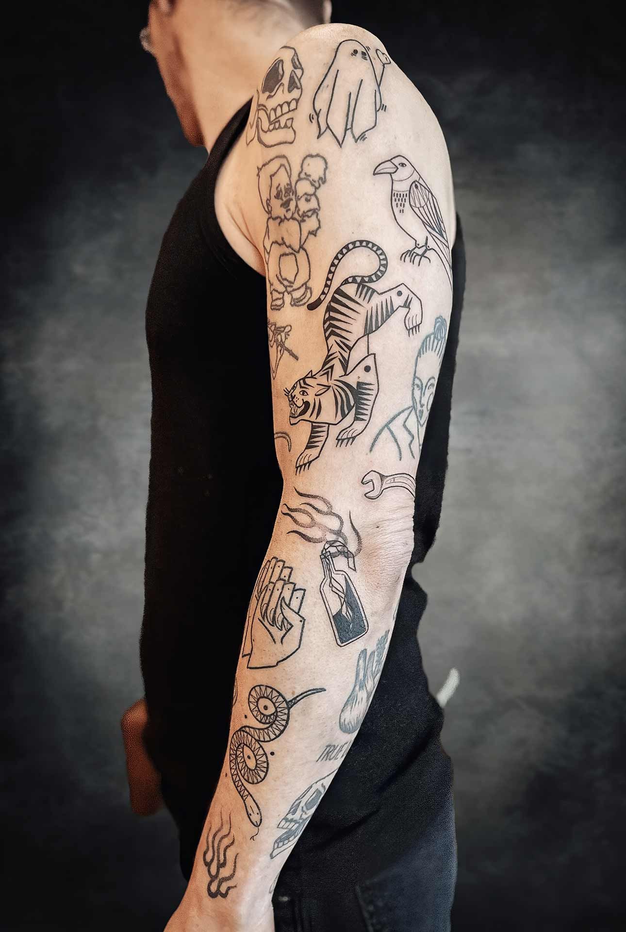 Un homme a de nombreux tatouages sur son bras, dont un tigre et un oiseau