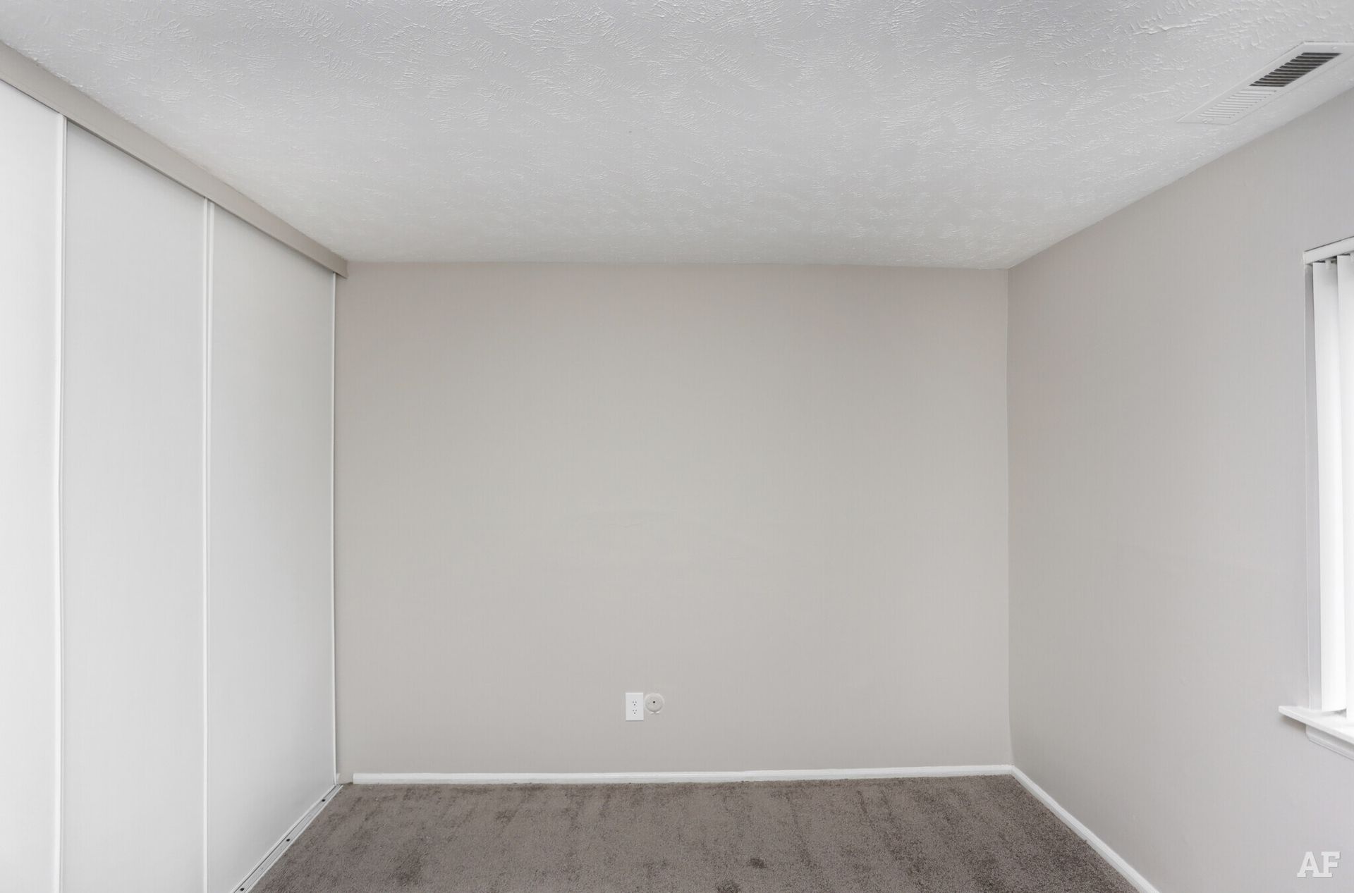 Empty room with gray walls, carpet, and built-in closet.