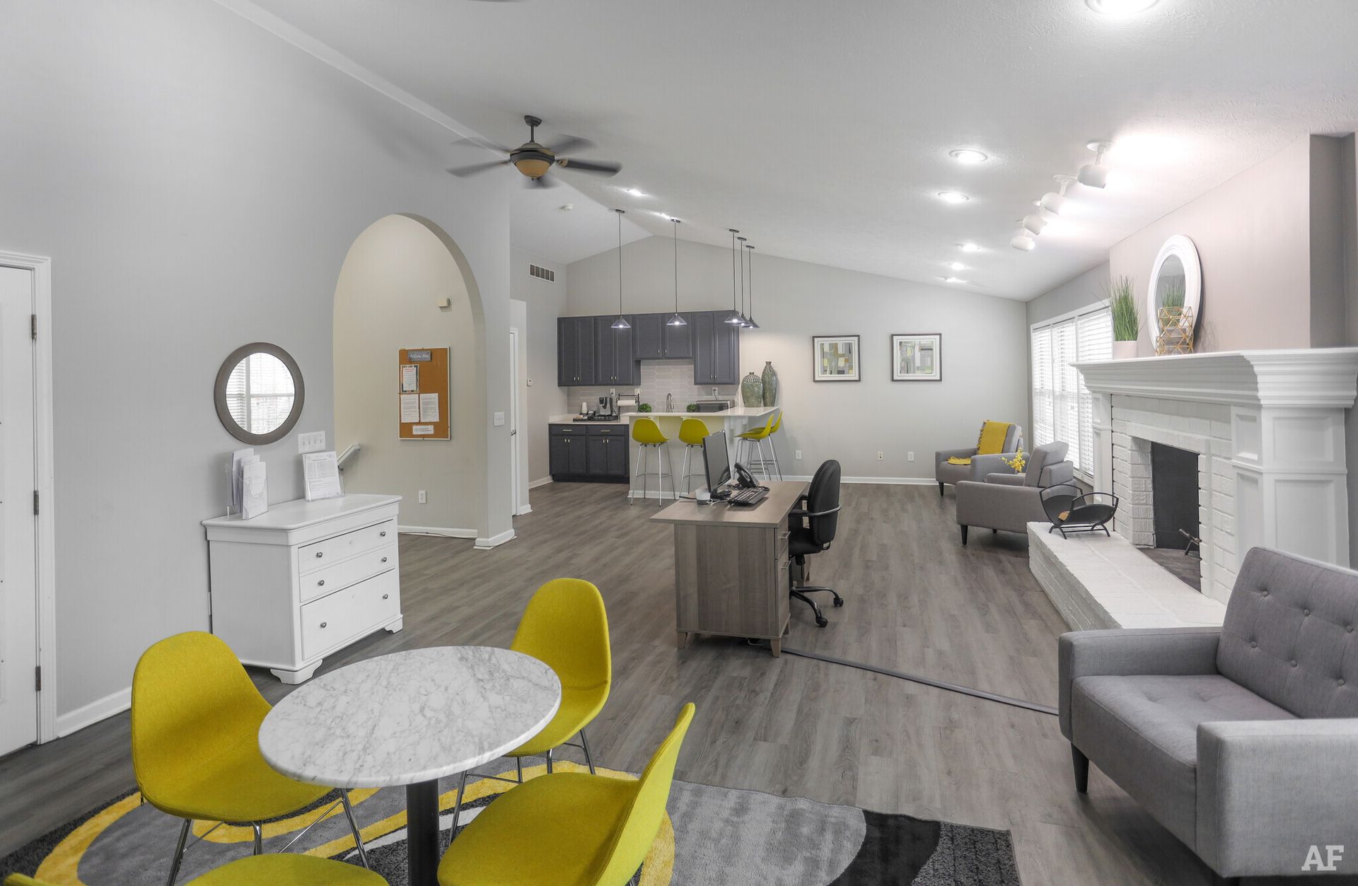 Spacious open-concept living area with kitchen, fireplace, dining table, and yellow and gray furniture.