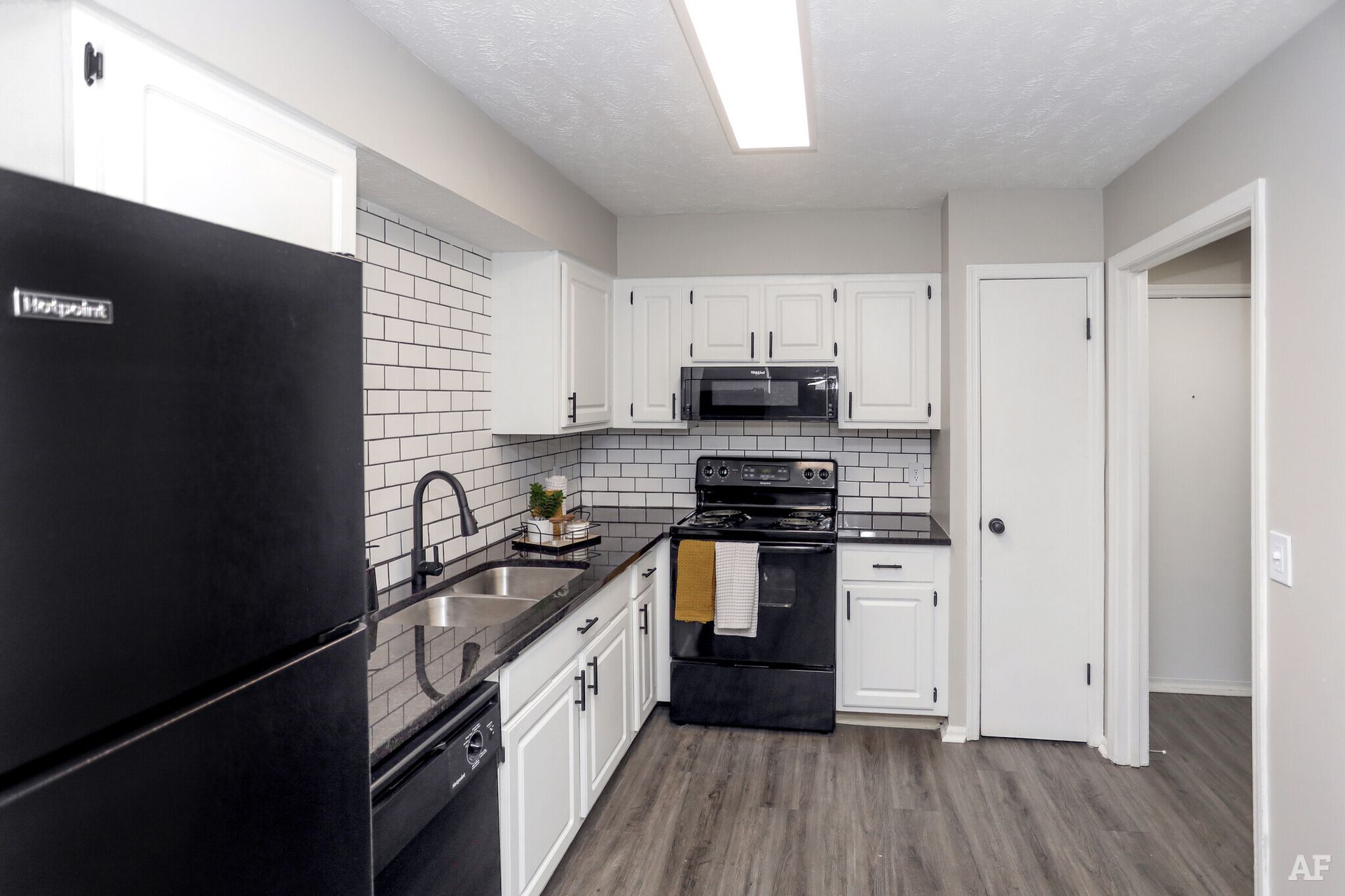 Modern kitchen with black appliances, white cabinets, and gray countertops.