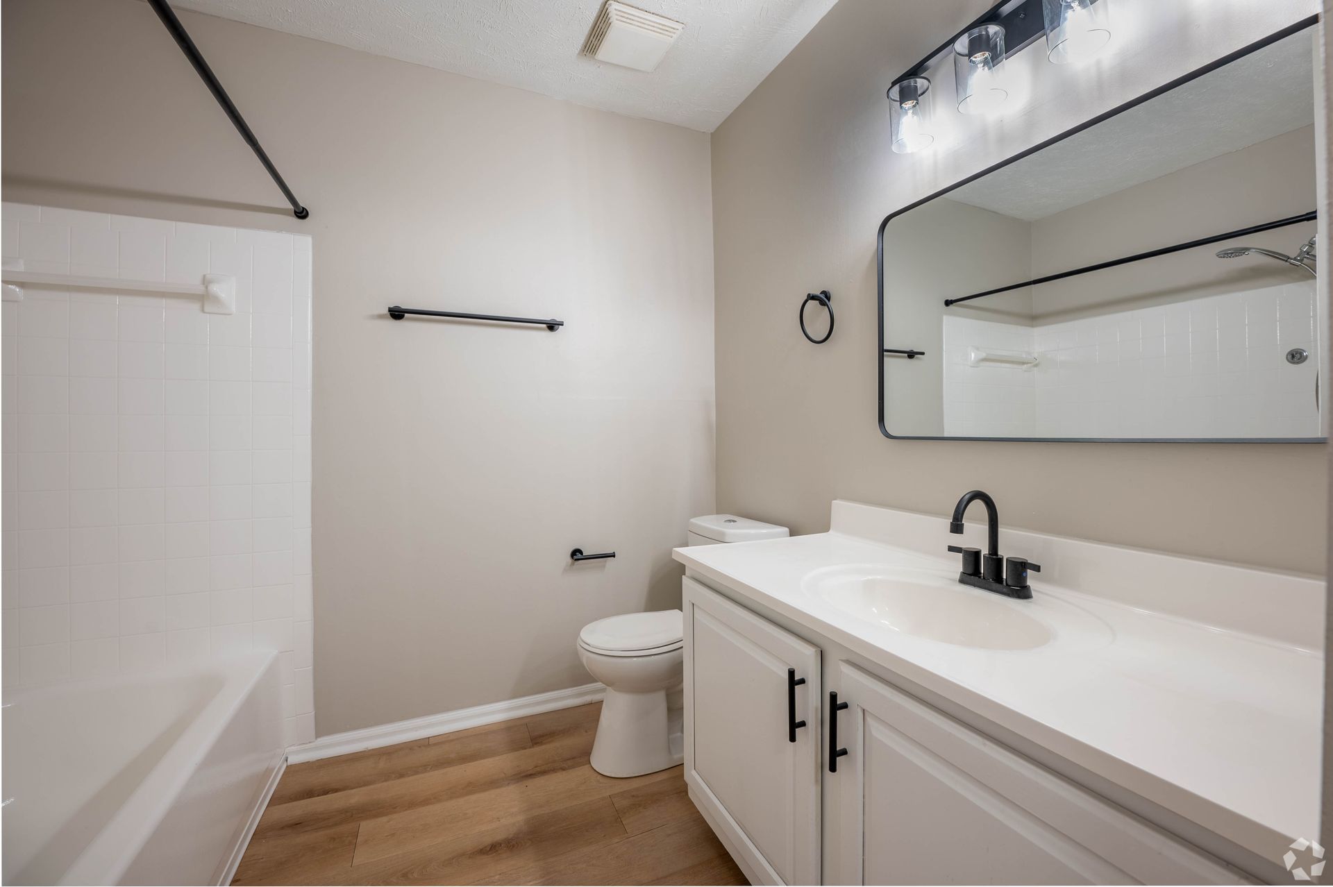 Bathroom with white vanity, black fixtures, and a shower/tub combo.