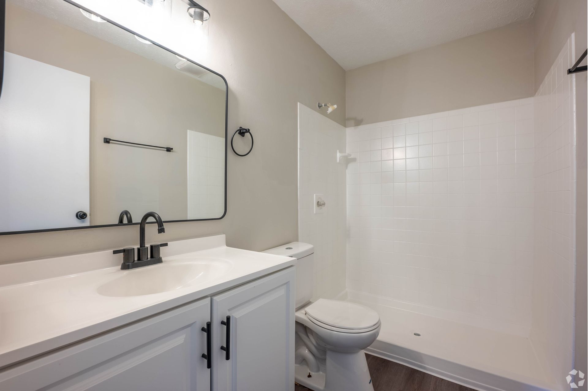Bathroom with white vanity, toilet, and shower, black accents.
