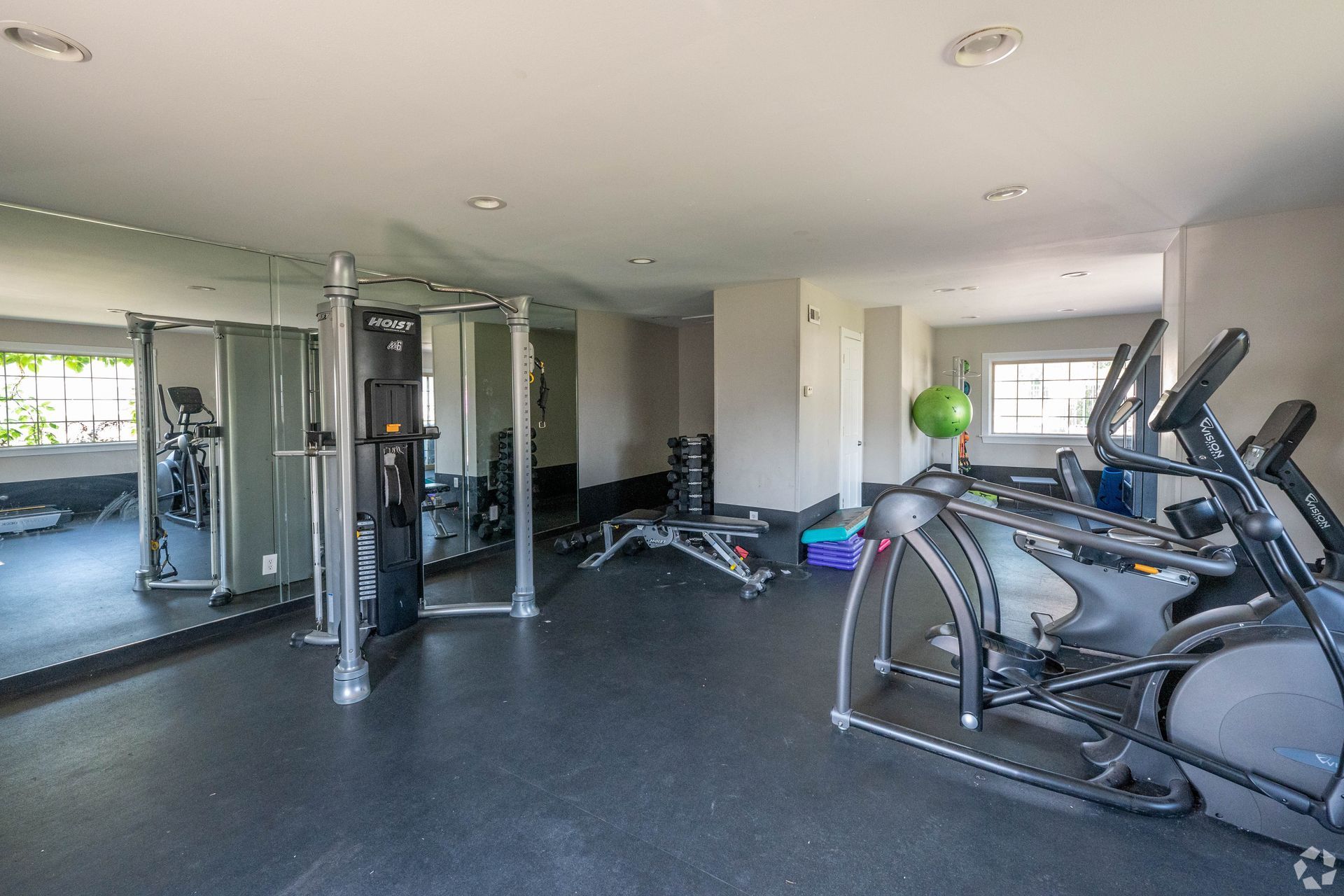 Gym with cardio machines, weight machines, free weights, and a large mirror.