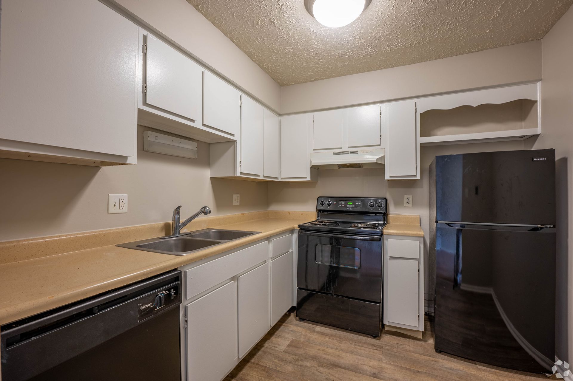 White kitchen with dark appliances and tan countertops.