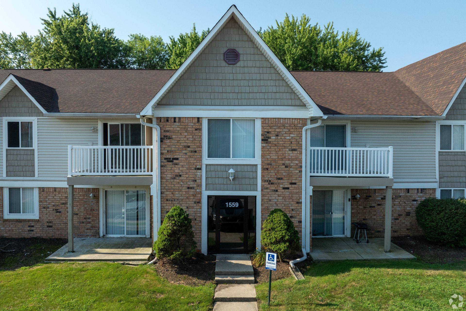 Apartment building exterior with brick facade, balconies, and green lawn.