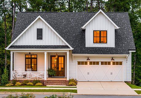 White farmhouse with a dark gray roof and two-car garage.