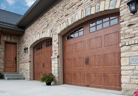 Brown garage doors with arched tops and stone facade.