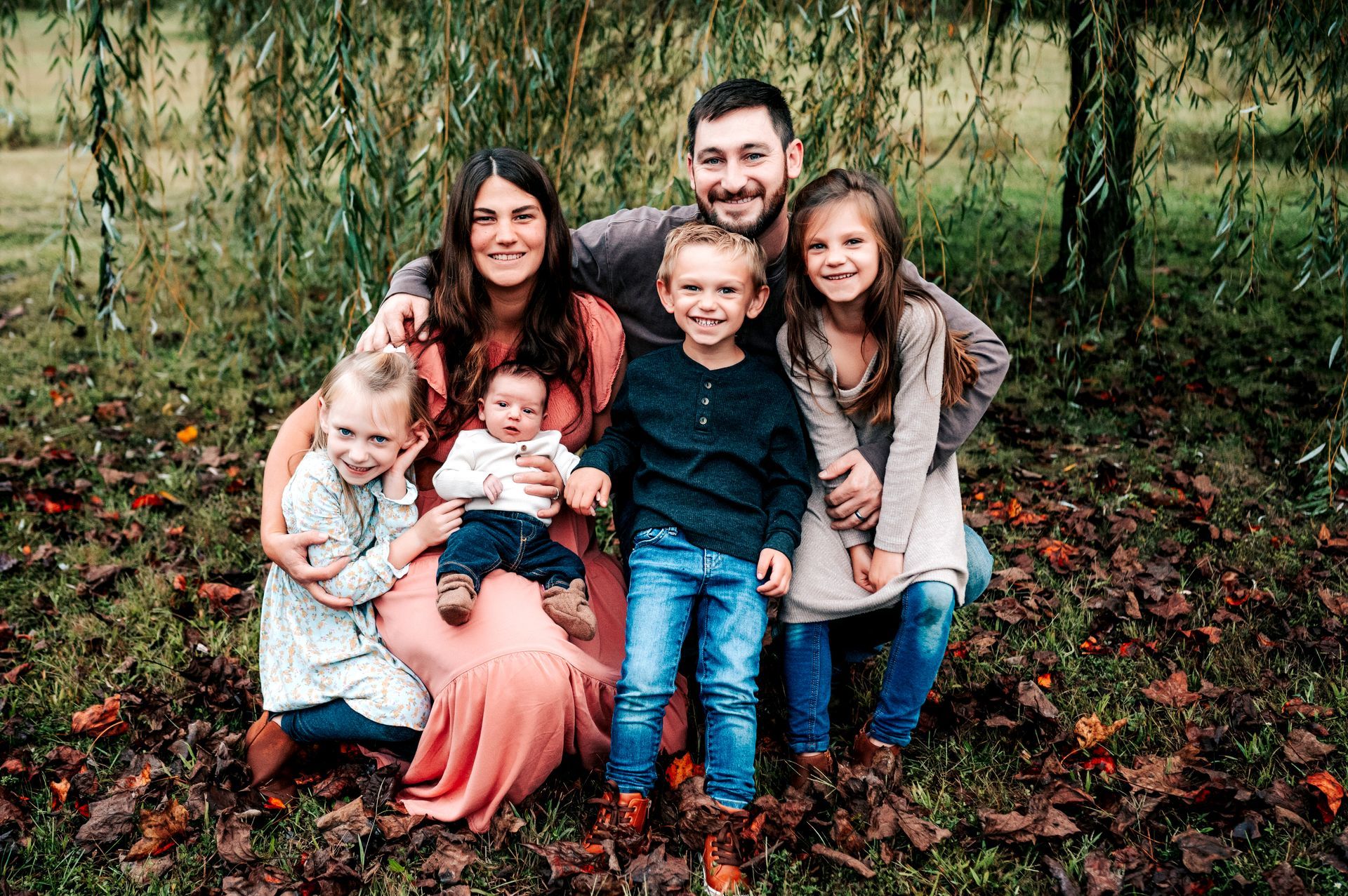About the Owner Family of six poses outside: parents, four young children smiling, fall foliage.